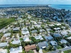 Aerial view of a charming coastal neighborhood with tropical homes nestled among palm trees, just minutes from pristine beaches.