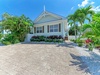 Charming coastal cottage surrounded by lush tropical landscaping and vibrant palms, offering a peaceful retreat in a prime location with dedicated parking and private entrance.