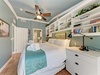 Unwind in your thoughtfully designed bedroom, featuring soft linens, built-in bookshelves, and a ceiling fan to keep you comfortable after days spent exploring the coast.