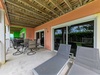 Your private patio invites you to unwind on loungers or gather at the dining table, with a BBQ ready for easy outdoor meals and views of the lush garden beyond.