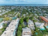 Aerial view of a tropical coastal neighborhood with palm-lined streets, residential homes, and ocean views stretching to the horizon.