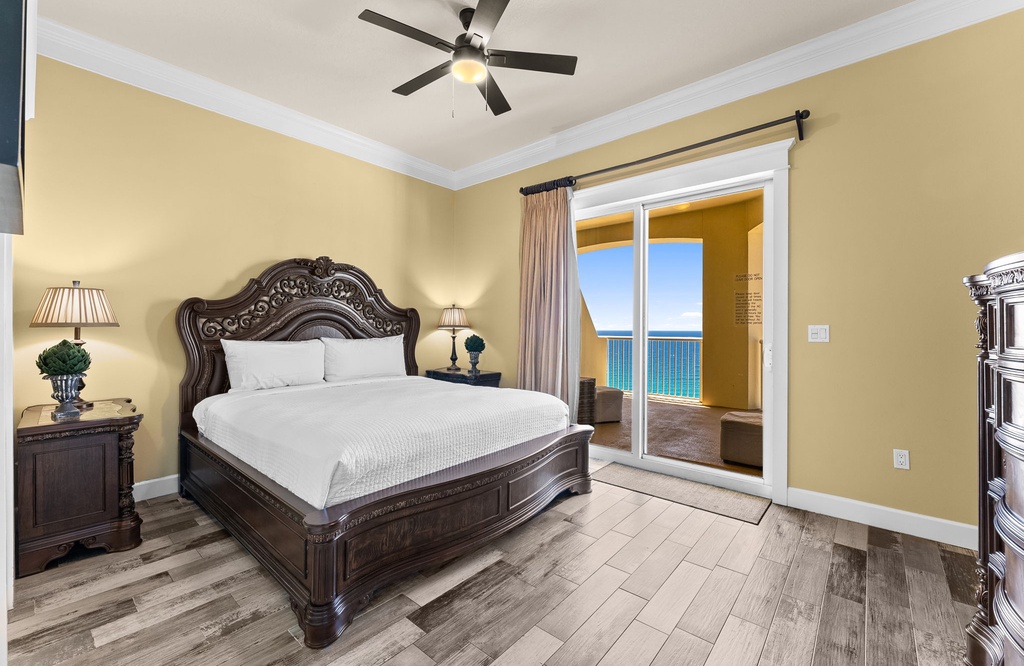 Spacious bedroom with classic wooden bed and ocean view balcony access.
