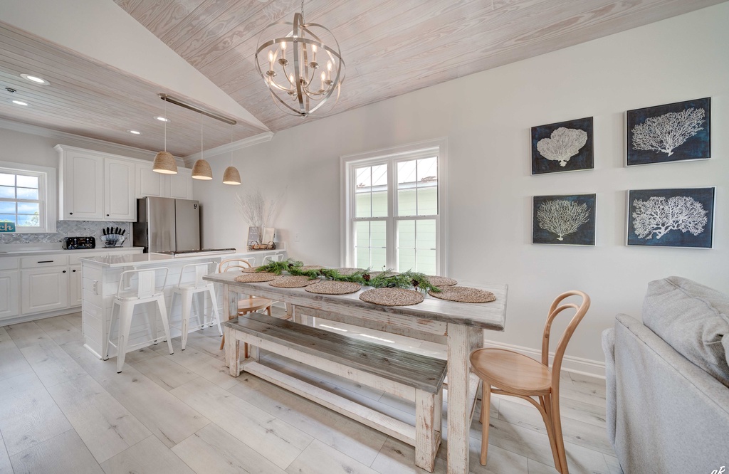 Rustic dining area with a large wooden table and modern kitchen in the background
