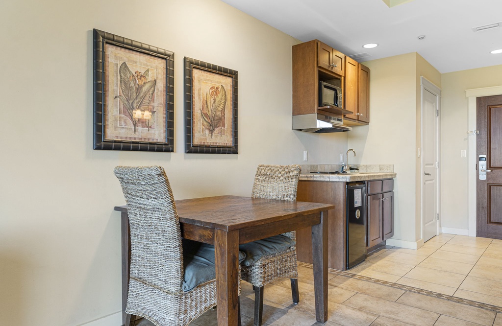 Cozy dining area with wicker chairs adjacent to a compact kitchen space.