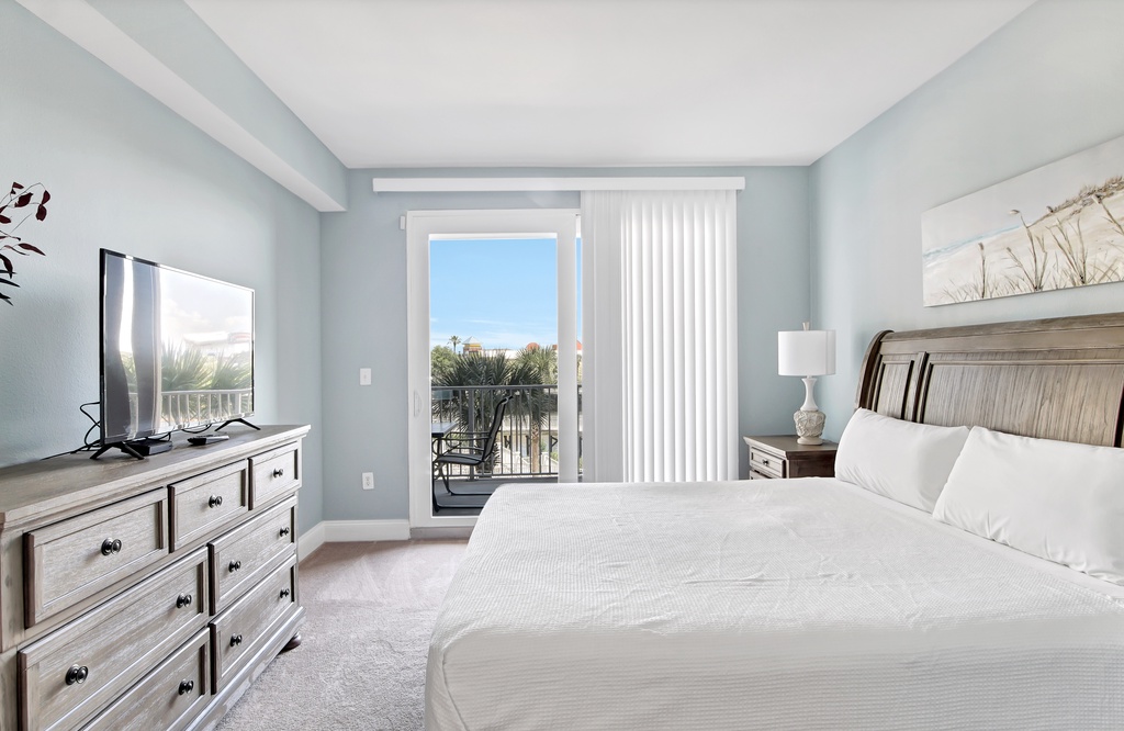 bright bedroom with balcony access and coastal views