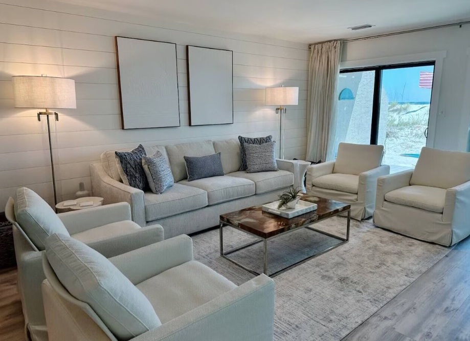 Sink into plush seating in your bright living room, where coastal light pours through sliding doors and neutral tones create a serene retreat for unwinding together.