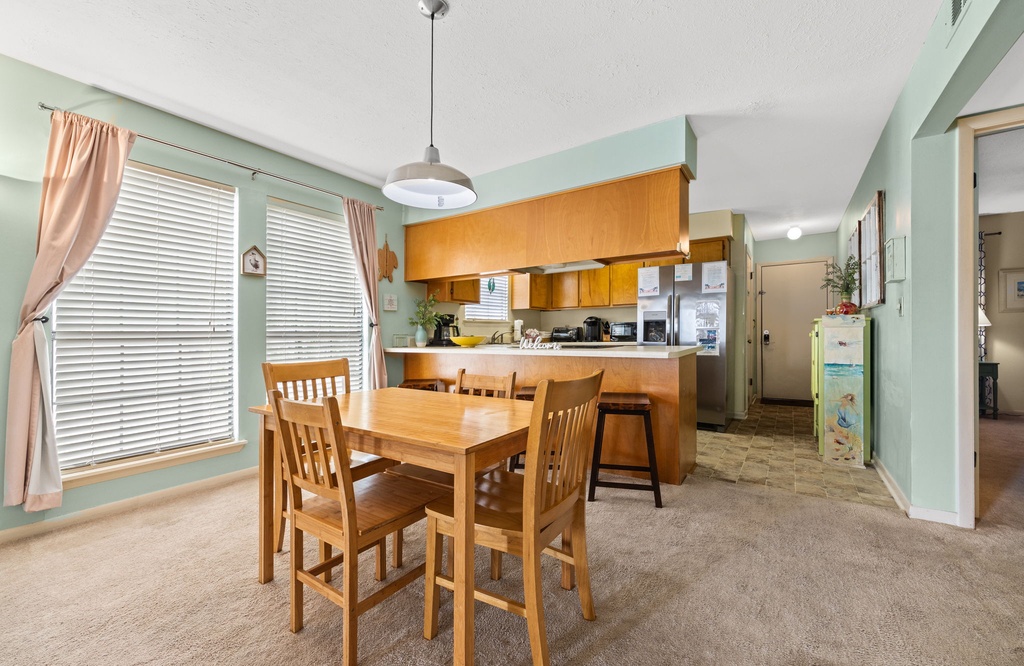 Dining area with natural light and a view into the kitchen featuring wooden cabinetry.
