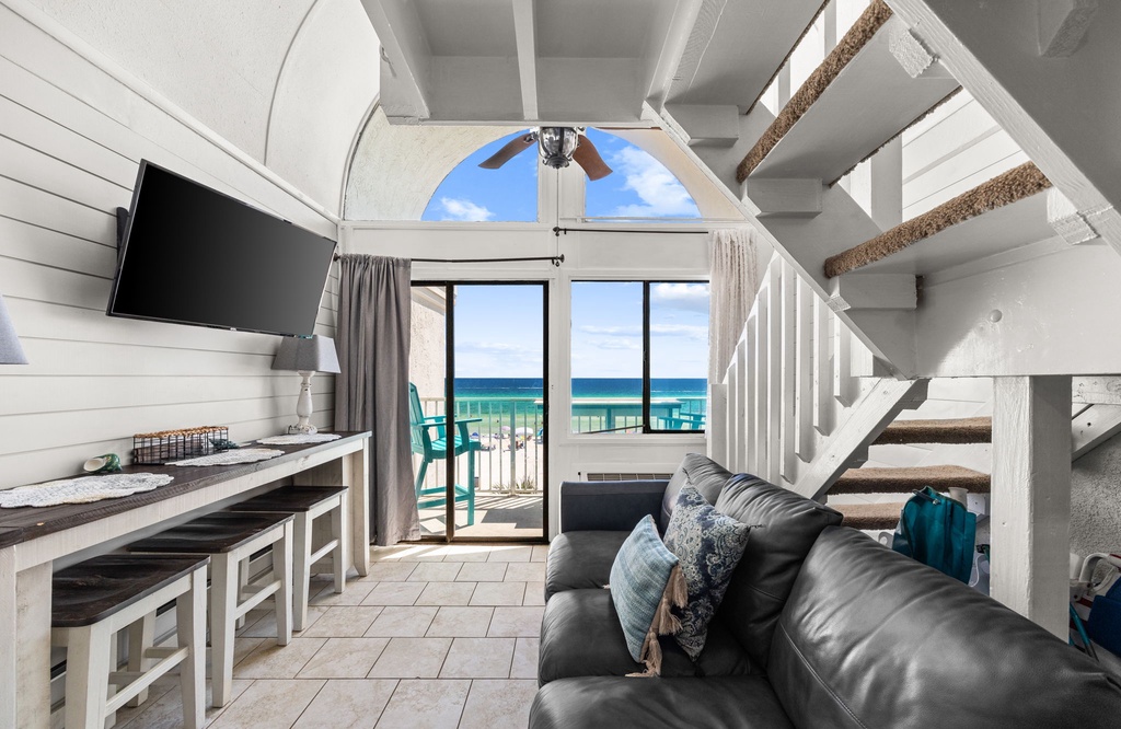 Relax on your plush leather sofa while gazing at the stunning turquoise waters through your glass balcony doors. The open, airy loft-style space invites you to unwind with beachy coastal charm and modern comfort.