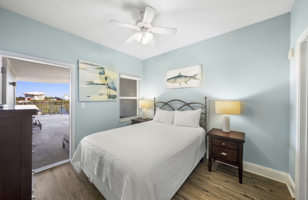 Cozy bedroom with coastal artwork and access to a private balcony.