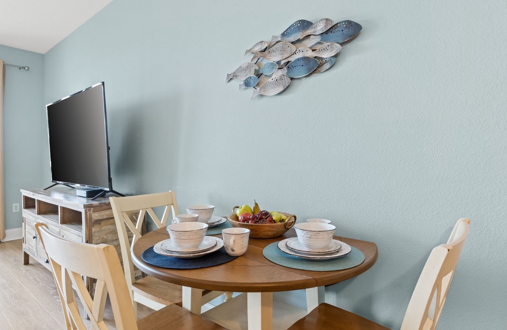 Cozy dining area with a round wooden table set for four and a wall-mounted fish decor.