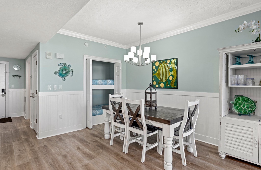 Dining area with coastal-themed decor and a built-in bunk bed for added sleeping space
