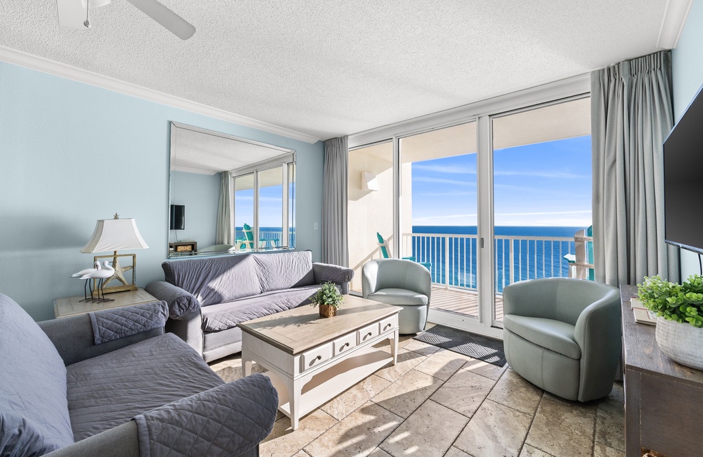 Relax in your oceanfront living room where calming blue walls and comfortable seating create the perfect backdrop for endless sea views through floor-to-ceiling windows.