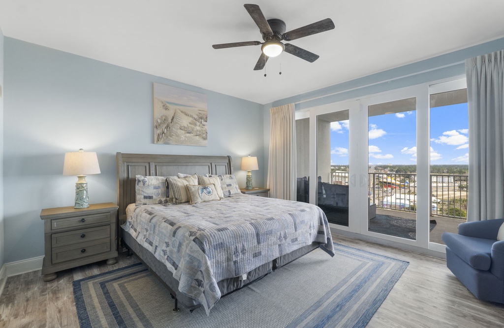 Relax in this bright bedroom with a balcony view and modern ceiling fan.