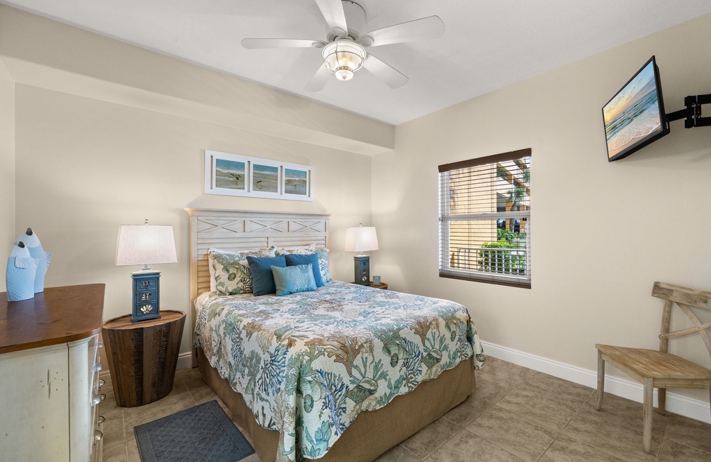 Cozy bedroom retreat w/ a plush bed, ceiling fan, & flat screen TV to wind down after a beach day.