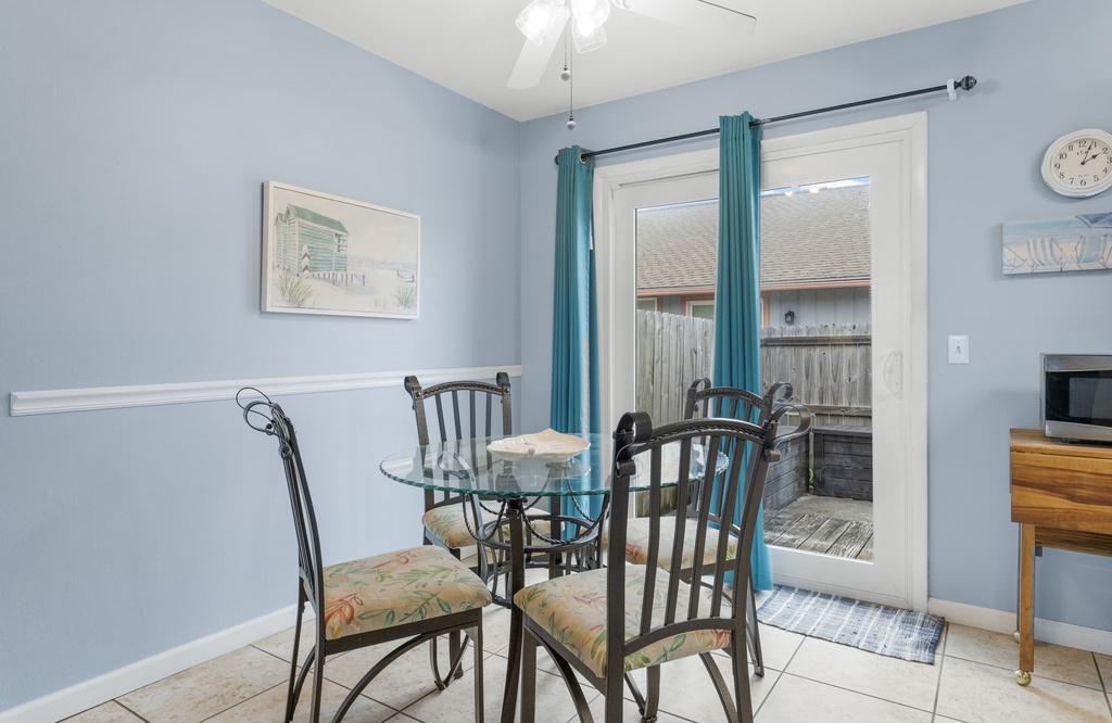 Dining area with glass table and access to a private outdoor space.
