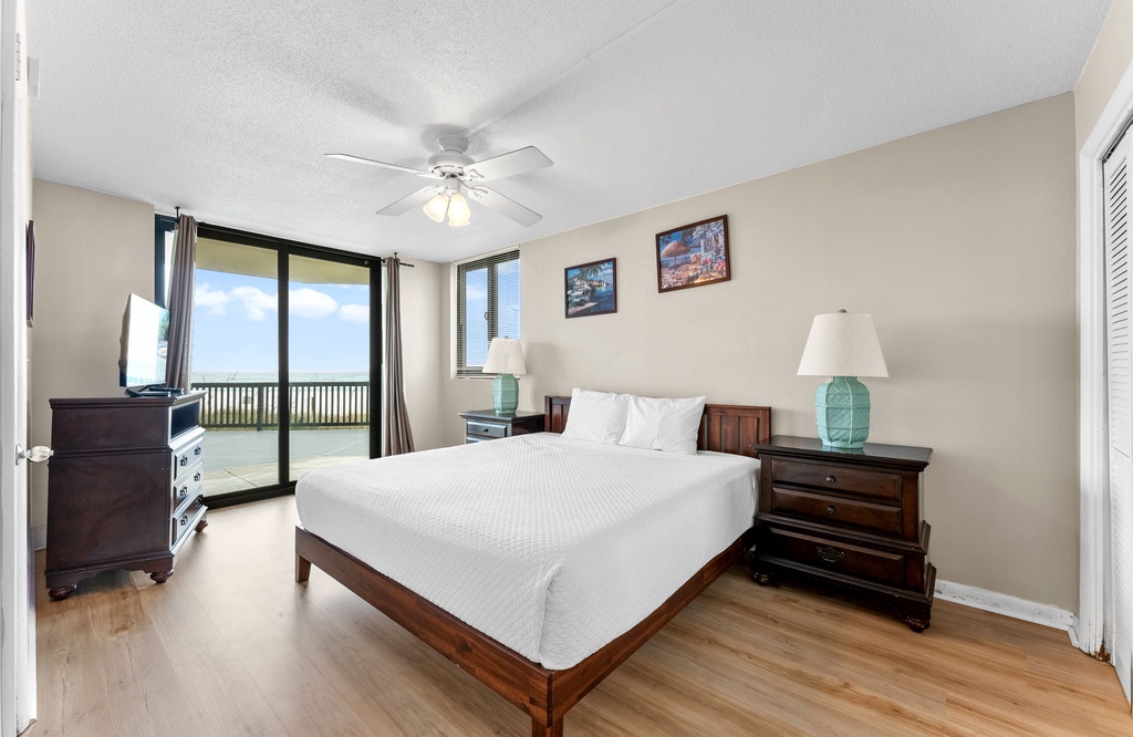Spacious bedroom with a king-size bed and balcony access offering ocean views.