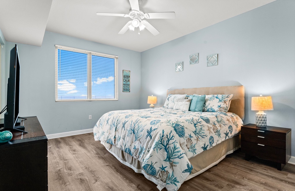 Relax in this coastal-themed bedroom with natural light and modern flooring.