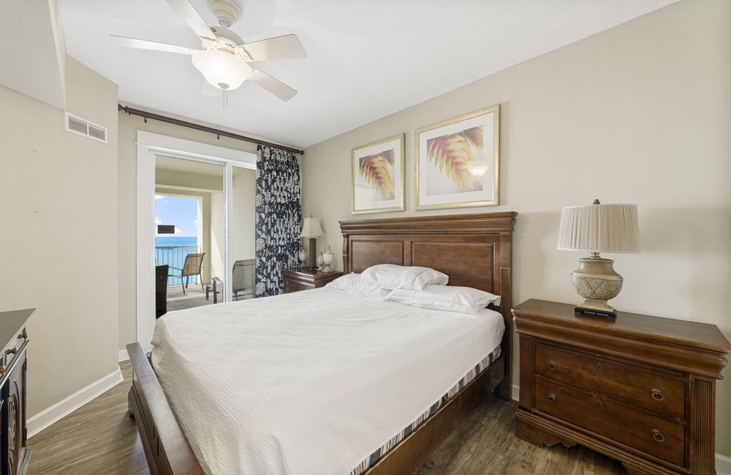 Relax in this cozy bedroom with a view of the balcony and ocean beyond.