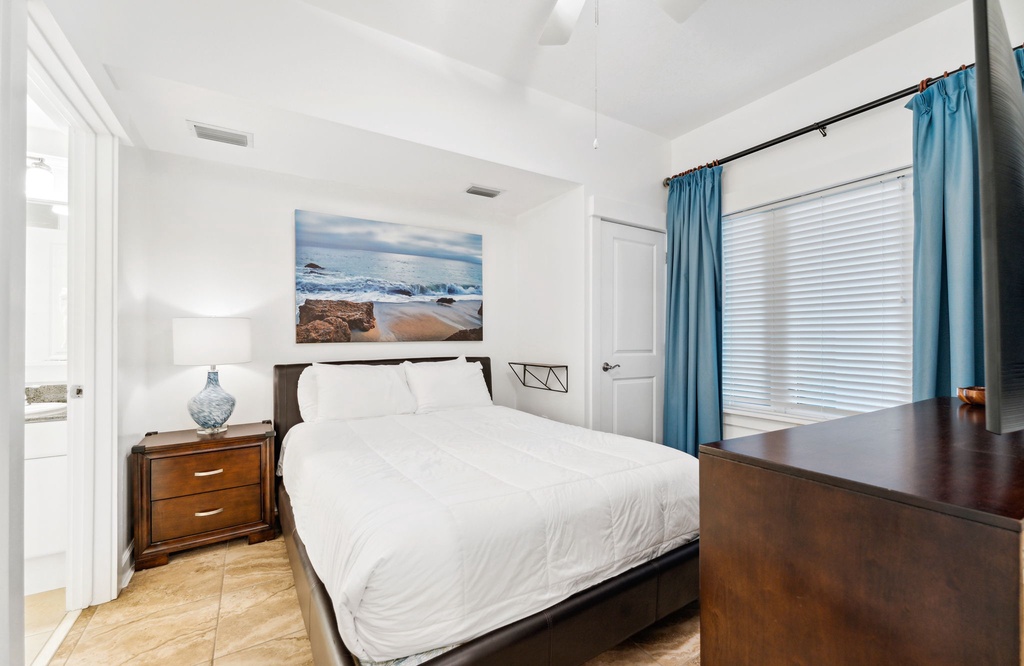 Cozy bedroom with a beach-themed artwork and natural light from the window.