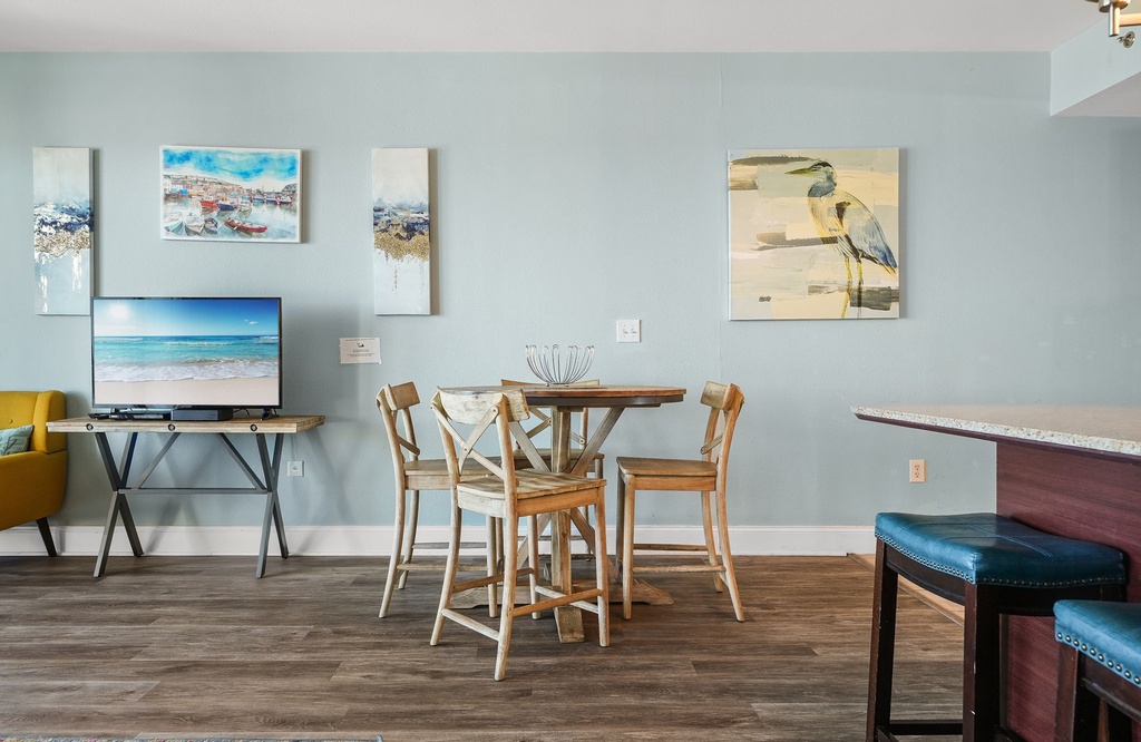 Dining area with wooden table and coastal-themed artwork in a modern setting