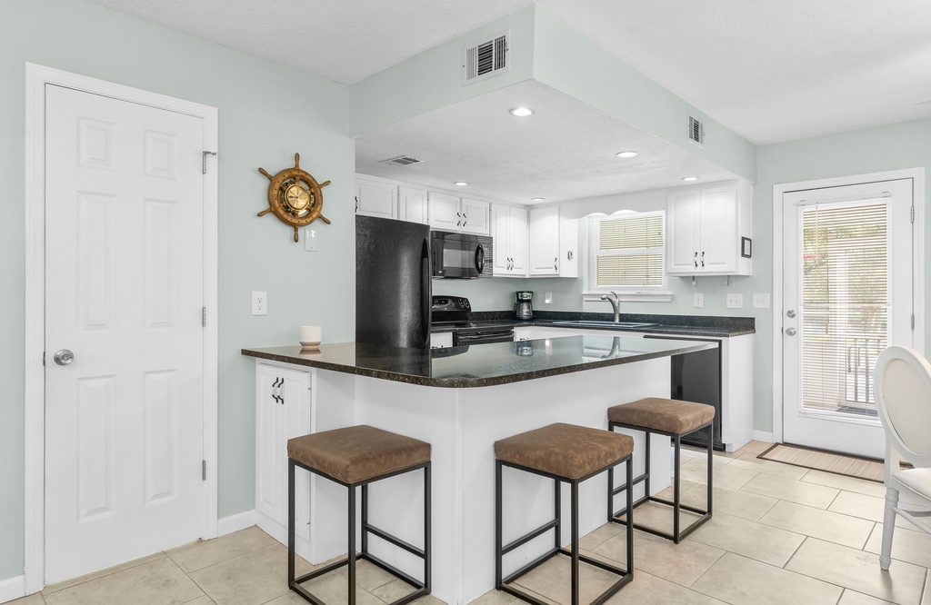 modern kitchen with black appliances and a breakfast bar with seating