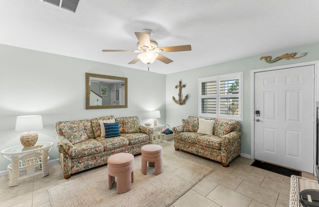 Cozy living room with floral sofas and natural light from the window.