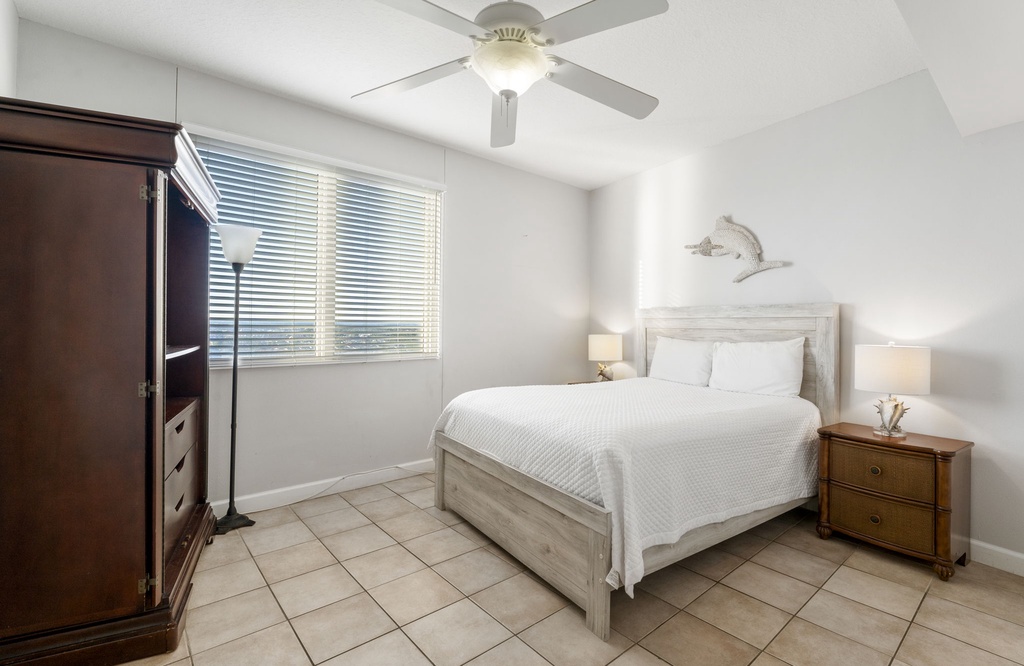 Bright bedroom with a white wooden bed frame and natural light from a large window