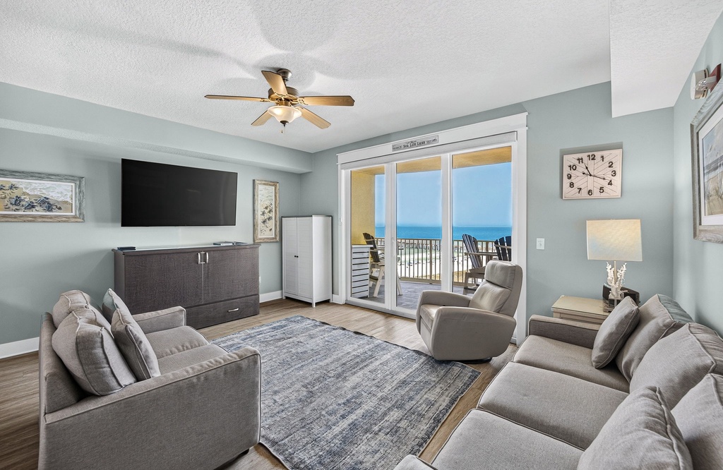 Relax in this serene living room where soft gray tones meet stunning ocean views through your private balcony doors. Comfortable seating invites you to unwind while gentle sea breezes drift in.