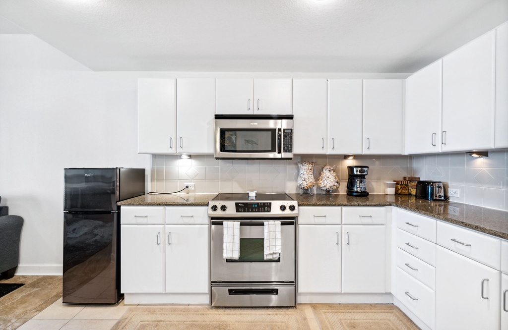 Modern kitchen with stainless steel appliances and ample white cabinetry.