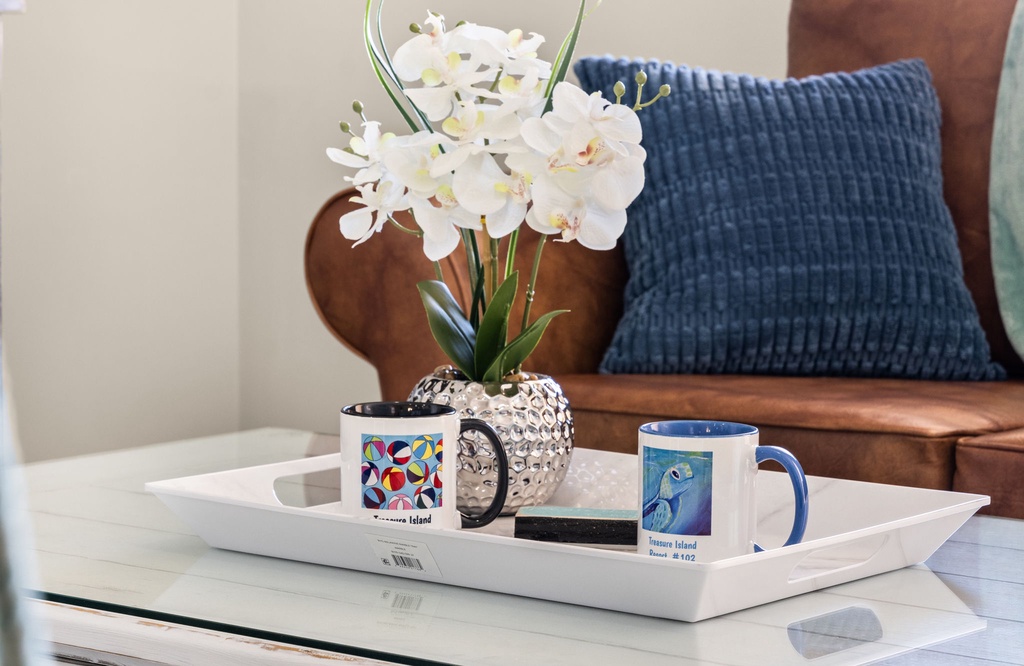 A modern living room detail featuring a decorative tray with mugs and a white orchid arrangement.