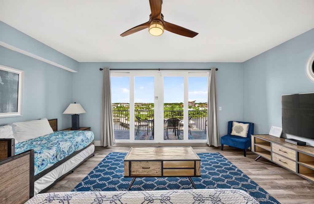 Sink into the coastal-blue calm of your suite, where glass doors frame your private balcony and gentle breezes drift through. Natural light fills the space as you unwind with scenic views just beyond.