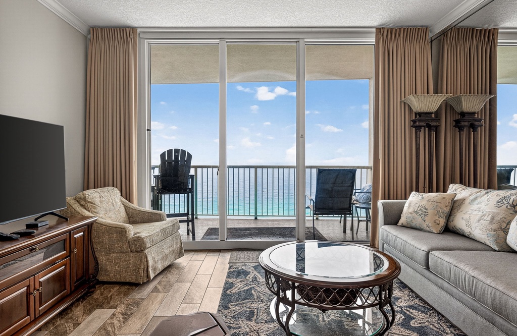 Step into your comfortable living space where floor-to-ceiling windows frame stunning ocean views.