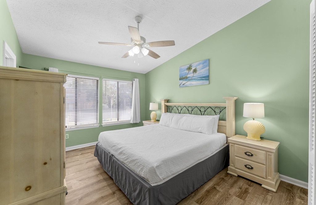 Relax in this bright bedroom with a bed and calming green walls.