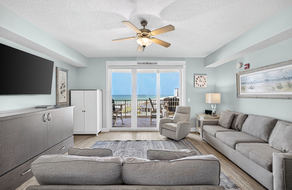 Step into this serene living room where calming blue-gray tones embrace you. Through the glass doors, your private balcony awaits with views of the ocean—your perfect spot for morning coffee or sunset drinks.