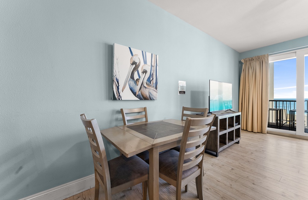 dining area with wooden table and chairs next to a balcony with ocean views