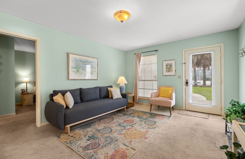 Settle into your serene living room with soft mint walls, plush seating, and French doors opening to outdoor tranquility.