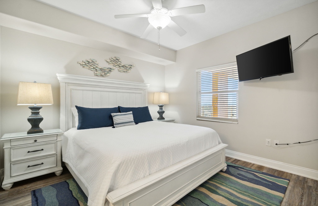 Bright and modern bedroom with a cozy bed and mounted flat-screen tv.