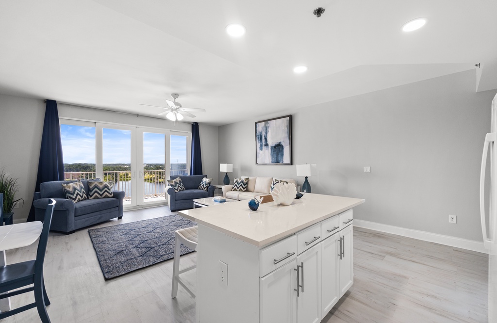 Settle into the open living area where the kitchen island invites casual meals and the large windows frame scenic views, with plush seating for relaxed evenings at home.