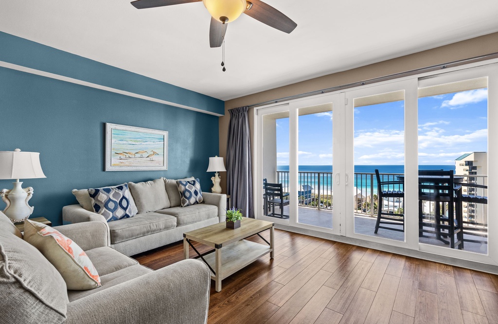 Unwind in your coastal retreat with plush seating, warm teal accents, and sweeping ocean views right from your balcony. The gentle hum of a ceiling fan and natural light create the perfect atmosphere for relaxation.