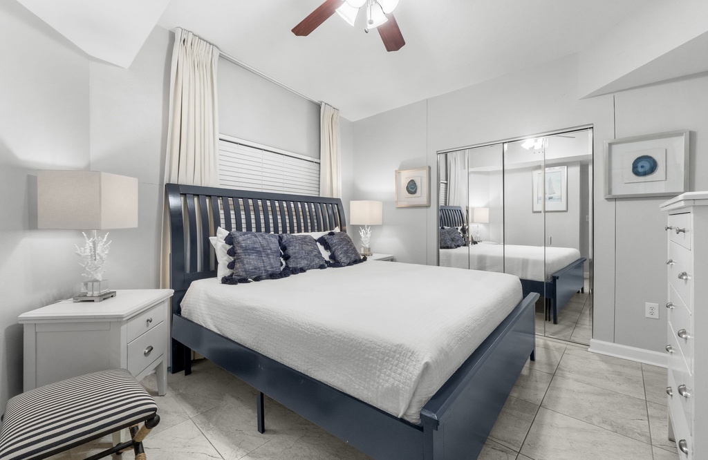 Modern bedroom with a navy bed frame and mirrored closet doors.