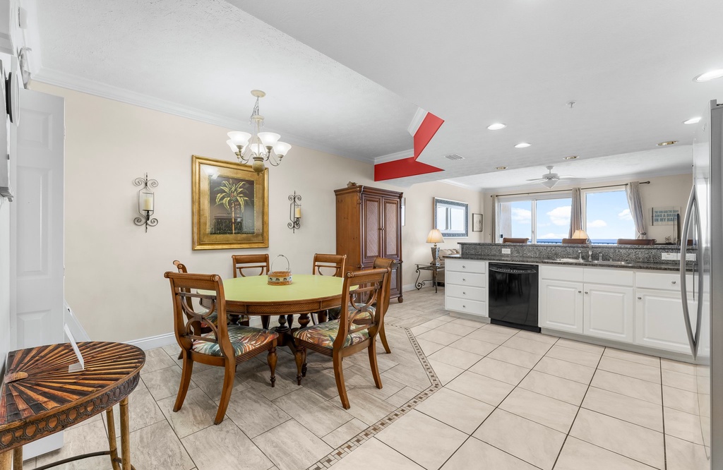Dining area with classic wooden furniture adjacent to a bright kitchen featuring large windows.