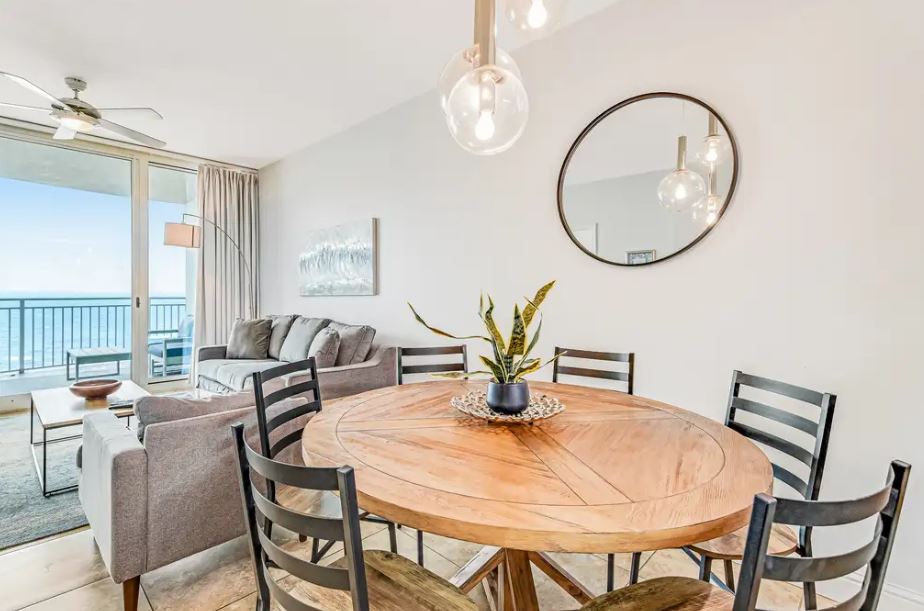 Gather around the elegant round table with ocean views stretching beyond, where modern comfort meets coastal charm in your open-plan retreat.