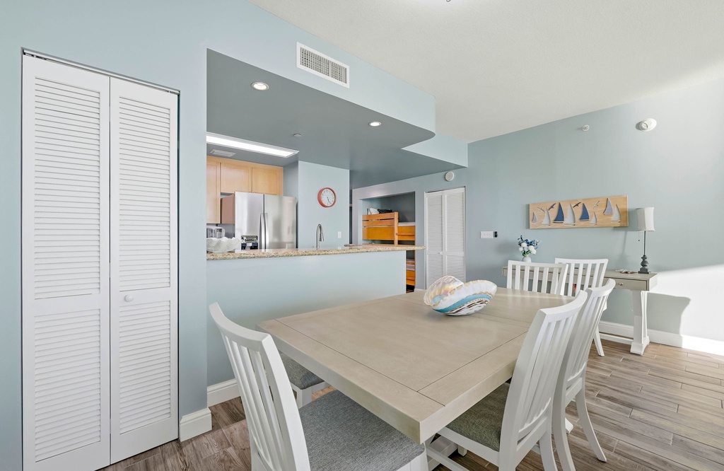 Dining area with coastal decor adjacent to a modern kitchen.