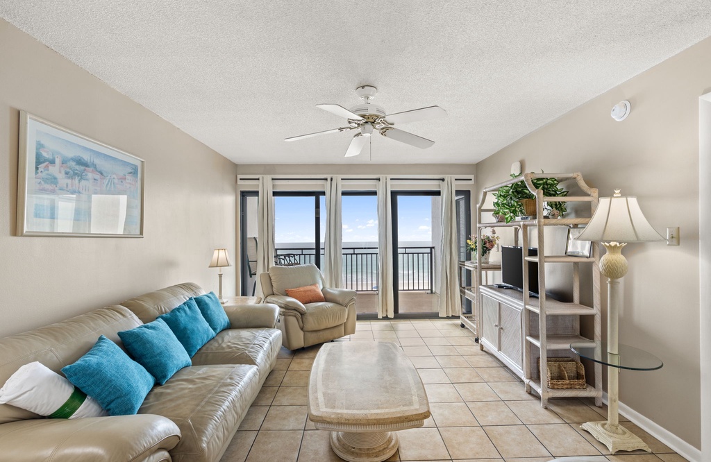 Sink into plush seating while ocean waves fill your view through floor-to-ceiling windows in this bright, airy living space.