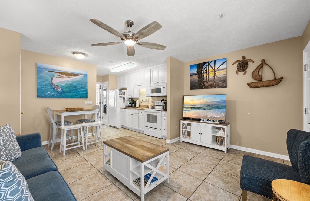 Relax in your coastal-themed living space with ocean artwork, comfy seating, and a fully equipped kitchen ready for your vacation meals.
