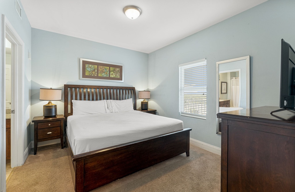 Cozy bedroom with a dark wood bed frame and soft blue walls.