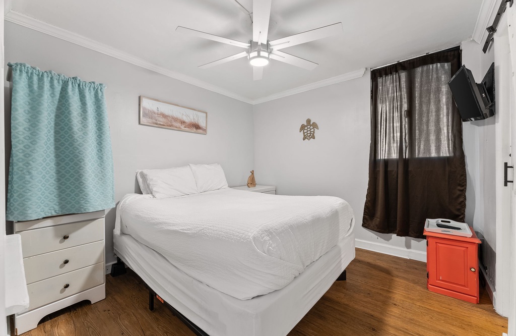 Cozy bedroom with a ceiling fan and natural wood flooring