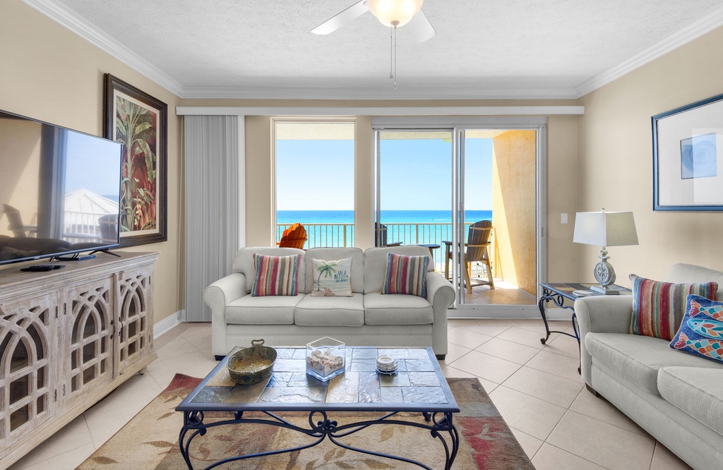 Unwind in your elegant living space with plush seating, tropical decor, and stunning ocean views through floor-to-ceiling windows.