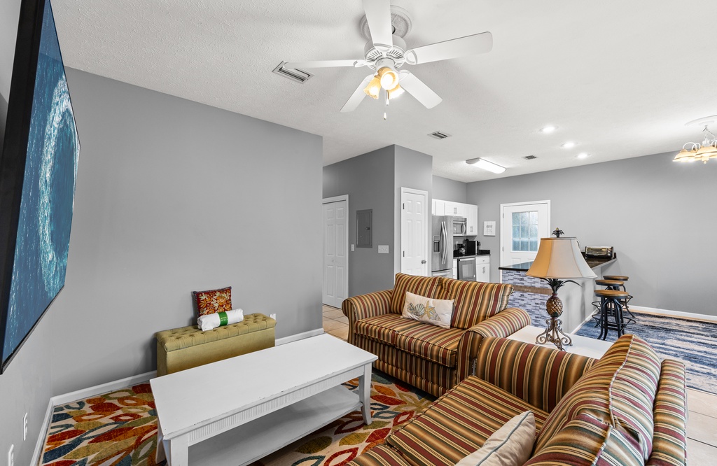 Settle into your bright, open living space where colorful coastal touches meet modern comfort. Stream your favorite shows on the large TV while the ceiling fan keeps you cool.