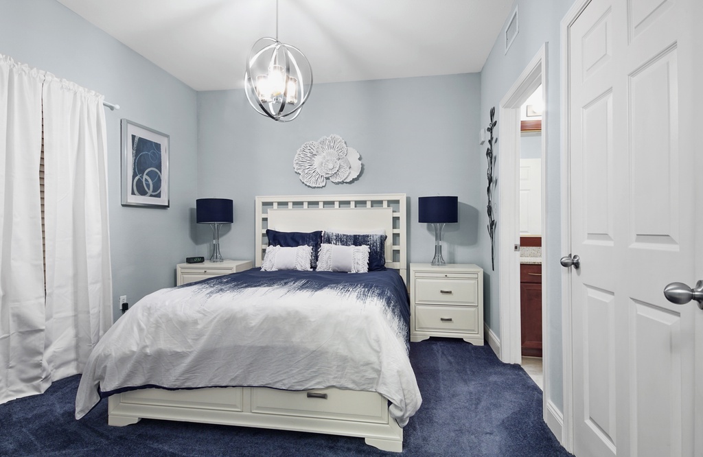 Cozy bedroom with a modern light fixture and calming blue accents.
